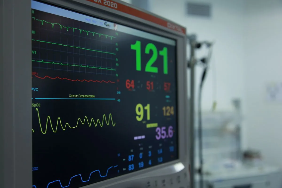 Hospital vital-signs monitor displaying heart rate and blood pressure readings in an intensive care room