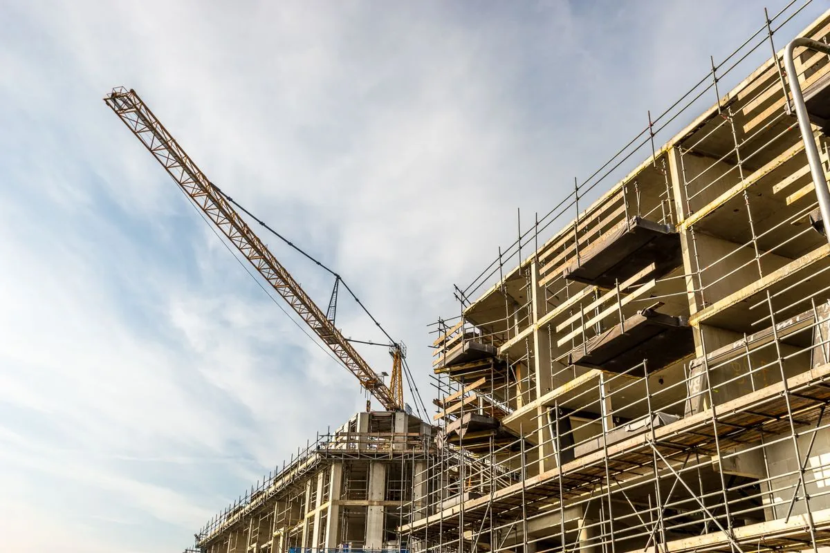 Tower crane above a concrete building under construction wrapped in scaffolding