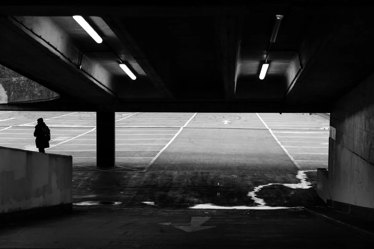 Dimly lit parking garage with a wet, poorly lit walkway