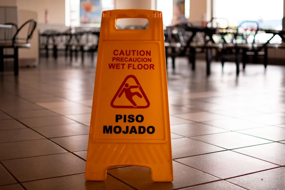 Yellow caution wet floor sign standing on a tiled floor