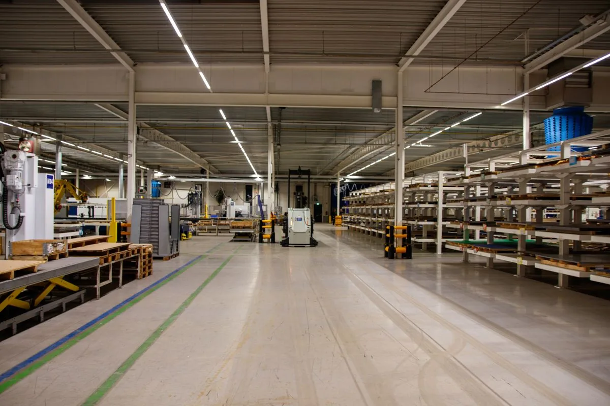 Aisle of an industrial plant lined with steel racking and machinery